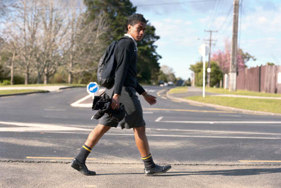 Image of a boy with black spiked hair walk past a driveway
